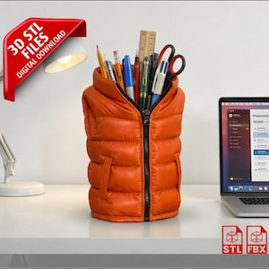 May include: An orange puffer vest-shaped desk organizer filled with pens, pencils, scissors, and a ruler. The organizer has a black zipper and pockets. A laptop and desk lamp are in the background. The image includes the text "3D STL FILES DIGITAL DOWNLOAD".