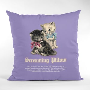 Puede incluir: Una almohada morada con un gráfico de dos gatitos. El texto "Screaming Pillow" está impreso en la almohada. El texto debajo del gráfico dice "Push your face into the pillow and scream at loud as possible for immediate smelt relief. This all natural devise is safe to ate multiple times a day. Soroaming mag be sakitituted for surening shen maputred."