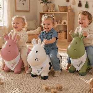 Könnte beinhalten: Drei Kinder reiten auf aufblasbaren Tierspielzeugen. Die Spielzeuge sind ein rosa Pferd, eine weiße Kuh und eine grüne Giraffe. Jedes Spielzeug hat ein weißes Halstuch mit einem Namen. Die Kinder lächeln und lachen in einem Spielzimmer.