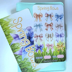 May include: A light teal planner with two cards. One card features the text "Spring Bows" and illustrations of various bows in pastel colours. The other card has a floral design with the text "Spring Bows".