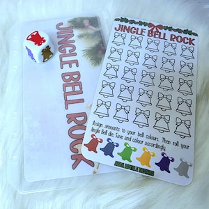 May include: A clear plastic pouch with the text "JINGLE BELL ROCK" next to a white die with red, gold, and blue bell icons. A card with bell illustrations and instructions is also visible.