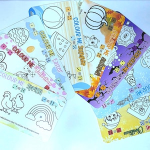 May include: A selection of rectangular colouring cards with seasonal themes, such as Easter, Valentine's, Spring, Summer, Halloween, Christmas, and Winter. Each card has a black and white illustration and the text "COLOUR ME" with dice icons.