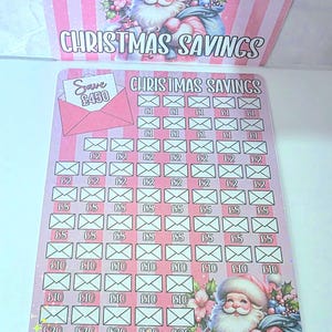 May include: A festive Christmas savings tracker in pink and white, featuring a Santa Claus illustration and the words "CHRISTMAS SAVINGS". The tracker is designed to save amounts from £1 to £20. It includes an envelope graphic with "Save £450".