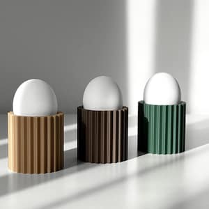 Può includere: Tre uova bianche in porta uova. I porta uova sono realizzati in materiale rigato e sono di colore marrone, marrone scuro e verde.