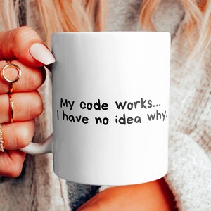 Może przedstawiać: Biały kubek do kawy z czarnym tekstem, który brzmi "Mój kod działa... Nie mam pojęcia dlaczego."