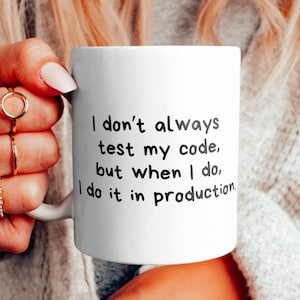 Op de afbeelding: Een witte keramische mok met zwarte tekst die luidt: "Ik test mijn code niet altijd, maar als ik het doe, doe ik het in productie."