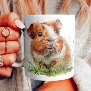 May include: White ceramic mug with a colorful illustration of a guinea pig in a grassy field. The guinea pig has brown and white fur and is looking directly at the viewer.
