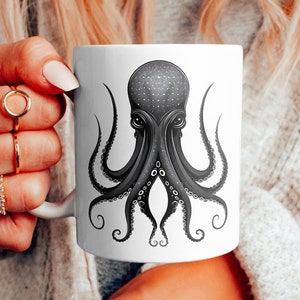 Op de afbeelding: Witte keramische mok met een zwart-witte illustratie van een octopus met een sterrenpatroon op zijn kop.