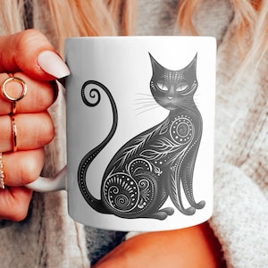 Op de afbeelding: Een witte keramische mok met een zwart-witte illustratie van een kat met ingewikkelde details. De kat zit met zijn staart om zijn lichaam gekruld.