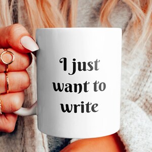 Può includere: Una tazza in ceramica bianca con testo nero che dice "I just want to write".