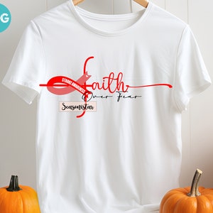 Peut inclure: T-shirt blanc avec un ruban rouge et les mots "Sensibilisation aux accidents vasculaires cérébraux" et "La foi sur la peur". Le mot "Seasonistar" est également imprimé sur le t-shirt. Des citrouilles sont en arrière-plan.