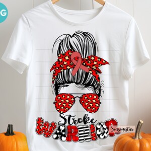 May include: White t-shirt with a red and black graphic of a woman with a messy bun, red and black bandana, and sunglasses. The text "Stroke Warrior" is written in red, black, and white letters.