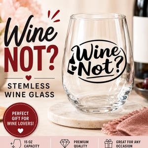 Op de afbeelding: Een helder, steelloos wijnglas met de tekst "Wine Not?" in zwart schrift. Het glas heeft een inhoud van ongeveer 444 ml en wordt gepresenteerd op een marmeren oppervlak. De afbeelding bevat ook een fles wijn en een roze servet.