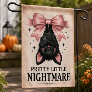 May include: A rectangular garden flag featuring a black bat hanging upside down from a large pink bow. The background is a light beige color with small black star accents. The text "PRETTY LITTLE NIGHTMARE" is printed in black at the bottom.