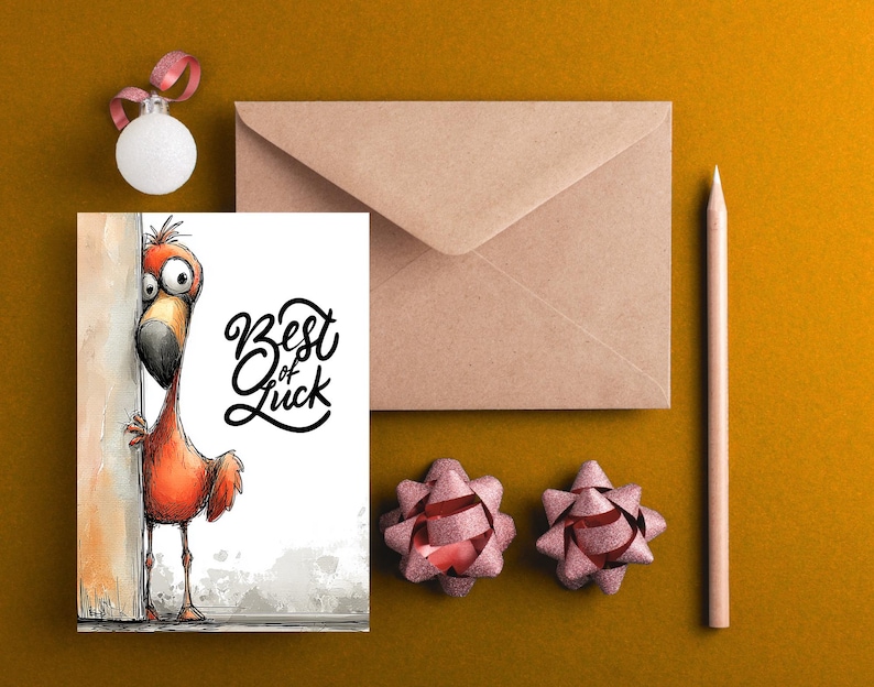 May include: A greeting card with a cartoon flamingo peeking from behind a wall, with the words "Best of Luck" in black script. The card is next to a brown envelope, a pencil, two pink bows, and a white ornament with a pink ribbon.