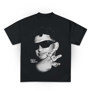 Op de afbeelding: Zwart T-shirt met een witte afbeelding van Patrick Mahomes die een zonnebril draagt en meerdere Super Bowl-ringen omhoog houdt. De tekst "Patrick Mahomes" is in wit onder de afbeelding gedrukt.