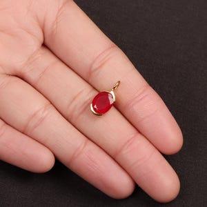 May include: A gold pendant with a red oval gemstone.