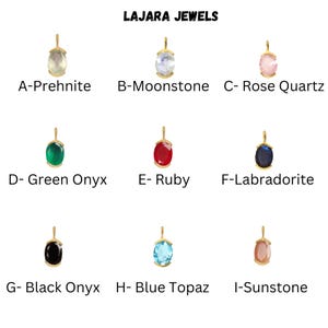May include: Nine gold pendants with different colored gemstones. The gemstones are prehnite, moonstone, rose quartz, green onyx, ruby, labradorite, black onyx, blue topaz, and sunstone. The pendants are labeled with the gemstone name and a letter.