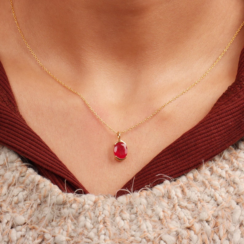 May include: A gold chain necklace with a red gemstone pendant.