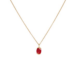 May include: A gold chain necklace with a red oval gemstone pendant.
