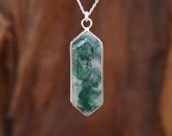 May include: A silver chain necklace with a green and white agate pendant. The pendant is shaped like a long, narrow rectangle with rounded edges.