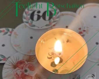 May include: A lit tealight candle in a clear holder, surrounded by decorative white coasters with floral and leaf designs. The coasters have the number 60 printed on them, with the words "Teelicht Botschaften" and "60. Geburtstag" in green.