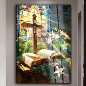 Könnte beinhalten: Ein religiöses Kunstwerk mit einem Holzkreuz mit einer Darstellung Jesu vor einem Buntglasfenster. Ein offenes Buch und weiße Lilien befinden sich im Vordergrund. Sonnenlicht scheint durch das Fenster und beleuchtet die Szene.