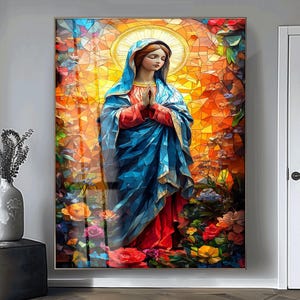 Könnte beinhalten: Gerahmtes Kunstwerk im Stil eines Buntglasfensters, das eine Frau in einem blauen Gewand mit gefalteten Händen zeigt. Das Kunstwerk zeigt einen Heiligenschein und ist von bunten Blumen in Rot-, Orange- und Gelbtönen umgeben. Der Hintergrund ist ein Mosaik aus warmen Tönen.