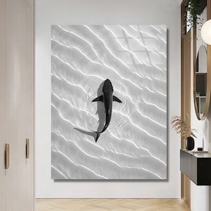 Könnte beinhalten: Ein Schwarzweißfoto eines Hais, der in klarem Wasser schwimmt. Der Hai ist von oben zu sehen, mit seiner Rückenflosse und seinem Schwanz. Das Wasser wellt sich und reflektiert das Licht, wodurch ein Muster aus hellen und dunklen Linien entsteht.