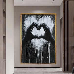 May include: Black and white abstract painting of two hands forming a heart shape. The background is a dark black with white paint splatters.