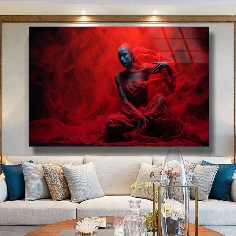 May include: A woman in a red sheer dress poses in a red smoke filled studio. The woman's skin is painted blue and she has a serious expression on her face.