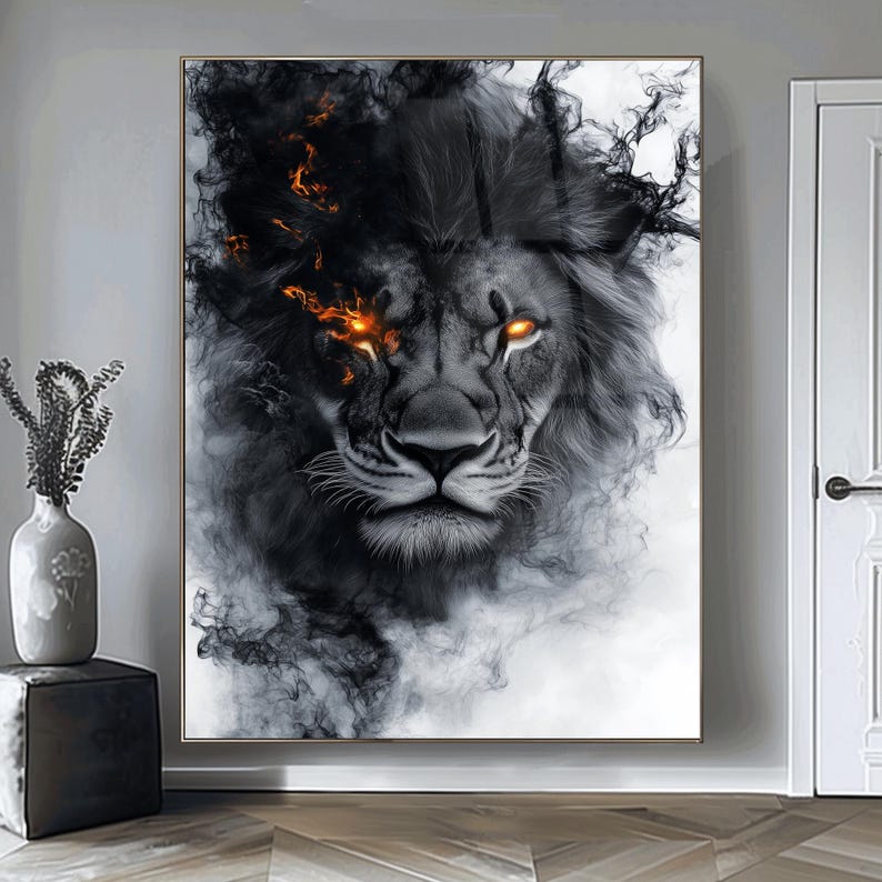 May include: A framed artwork featuring a lion's face with glowing orange eyes and a dark, smoky mane. The lion's fur is detailed in shades of gray and black, with wisps of smoke adding to the dramatic effect. The artwork is displayed on a wall.