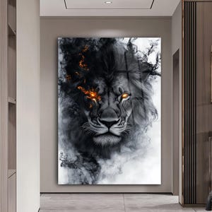 May include: A framed wall art print featuring a lion's face with a black and white smoky design. The lion's eyes glow with an orange light, and the artwork has a modern, artistic style. The artwork is displayed in a hallway.