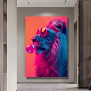 May include: A rectangular wall art print featuring a profile view of a lion wearing pink-rimmed sunglasses and blowing a large, bright pink bubblegum bubble. The lion is rendered in vibrant neon shades of blue, purple, and orange against a solid background.