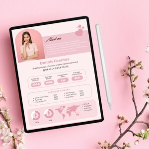 May include: A pink tablet screen displaying a resume for Dennis Fuentes, a graphic designer and content creator. The resume includes a headshot, social media statistics, services offered, and rates. The tablet is on a pink surface with a white stylus and a branch of white blossoms.