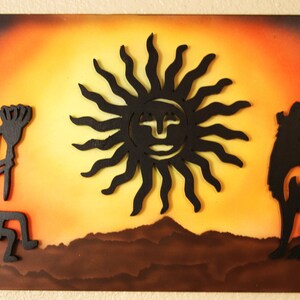 May include: A wooden wall art piece with a black silhouette of a Native American dancer, a sun with a face, and a wolf howling at the moon. The background is a sunset with orange, yellow, and brown colors.