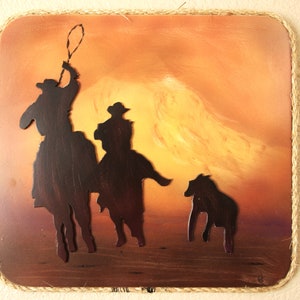 May include: A rustic wooden plaque with a rope border features a silhouette of three cowboys riding horses against a sunset background.