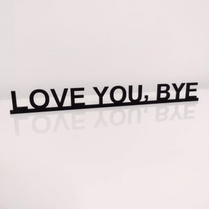 May include: Black wooden sign with the text "LOVE YOU, BYE" in all capital letters.