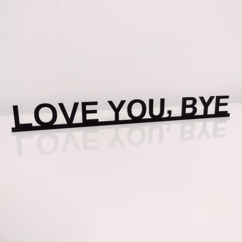 May include: Black wooden sign with the text "LOVE YOU, BYE" in all capital letters.