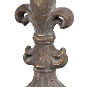 Könnte beinhalten: Eine dekorative, verzierte Fleur-de-lis-Skulptur in Gold und Grau. Die Skulptur ist aus einem strukturierten Material gefertigt und hat ein detailliertes Design.