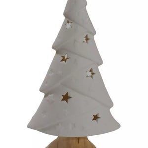 Könnte beinhalten: Weißer Keramik-Weihnachtsbaum mit Holzsockel. Der Baum hat ein sternförmiges Ausschnittmuster.
