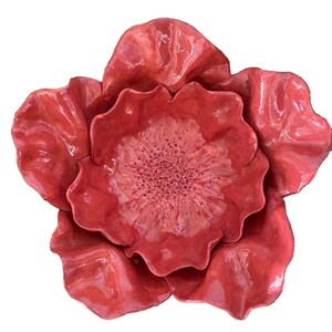 May include: A large, red ceramic flower with a textured center. The flower has five petals and is glossy.