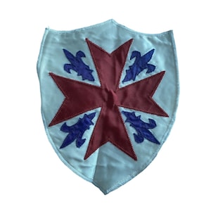 May include: A white shield-shaped patch with a red cross and blue fleur-de-lis designs.