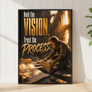 May include: A framed wall art print featuring a person kneeling and working on a stone block within a construction site. The text reads Hold the VISION. Trust the PROCESS. The scene is illuminated by warm golden light streaming through stone arches.