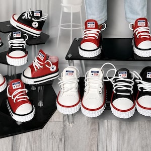 May include: A collection of low-top sneakers in red, black, and white, featuring white laces, white rubber toe caps, and textured white soles. Each tongue displays a rectangular label with the text Little Step and a star icon.