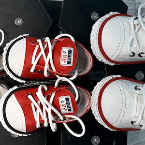 May include: Three pairs of low-top sneakers in black, red, and white. Each shoe features white laces, a white rubber toe cap, and a rectangular tongue label with the text LITTLE STEP and a star icon. The soles have a textured white trim.