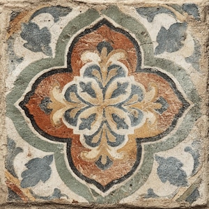 May include: A square, aged tile with a central floral design. The design features a four-petal shape with a mix of colors, including orange, blue, and cream, set against a weathered, beige background. The tile has a rustic, vintage appearance.