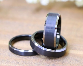 May include: Three black tungsten carbide rings with beveled edges. The rings are stacked on top of each other.