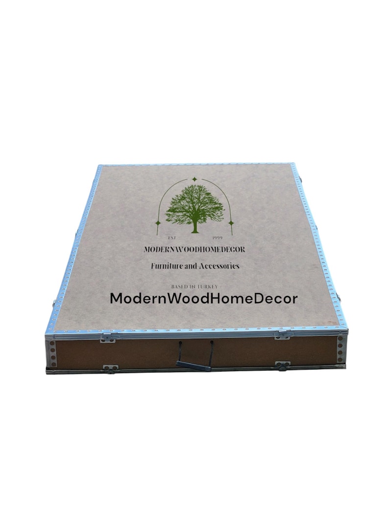 May include: A rectangular wooden storage box with metallic silver edges and a handle. The top surface features a green tree logo, the text EST 1999, MODERNWOODHOMEDECOR, Furniture and Accessories, BASED IN TURKEY, and ModernWoodHomeDecor.