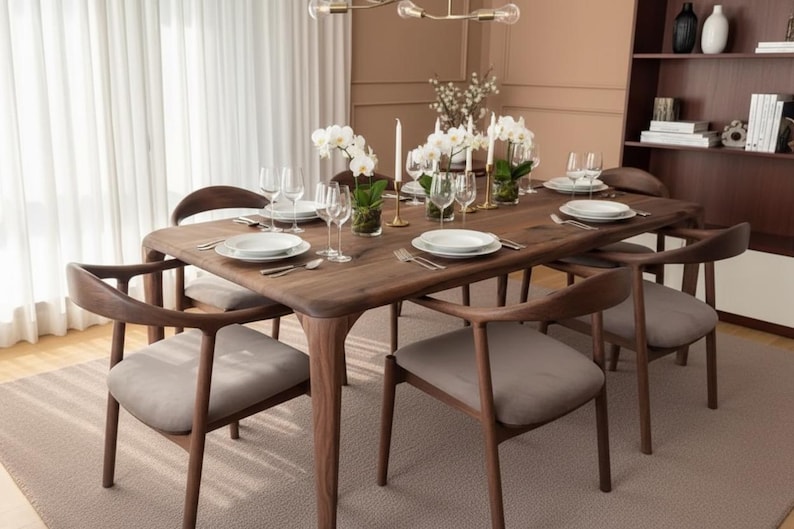 May include: A rectangular dark wood dining table with rounded corners and six matching chairs featuring curved backrests and light grey upholstered seats. The table is set with white plates, clear glassware, silverware, and white orchid centrepieces.